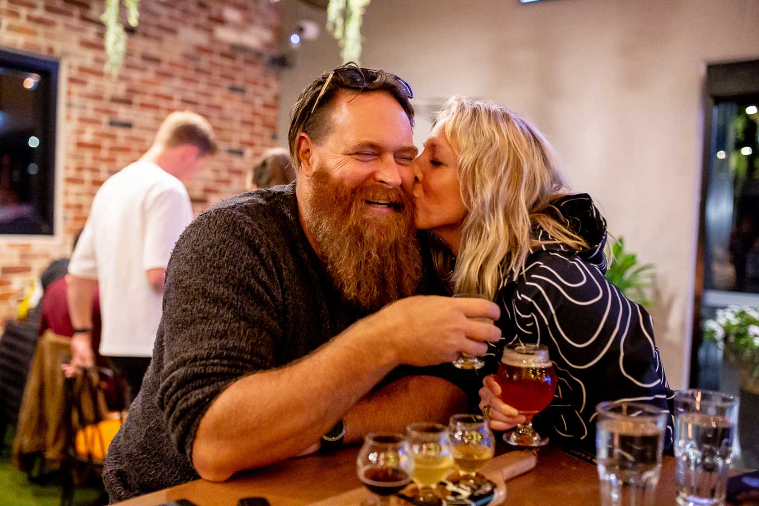 Woman kissing man on the cheek at a craft brewery